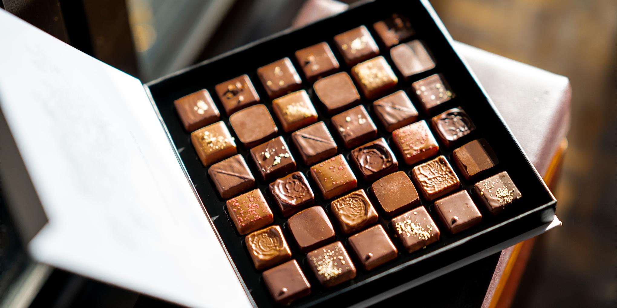une boite ouverte avec différentes pralines sur un fond foncé
