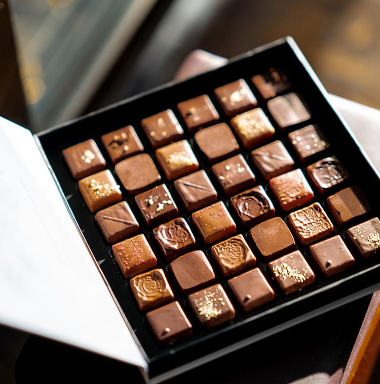 une boite ouverte avec différentes pralines sur un fond foncé